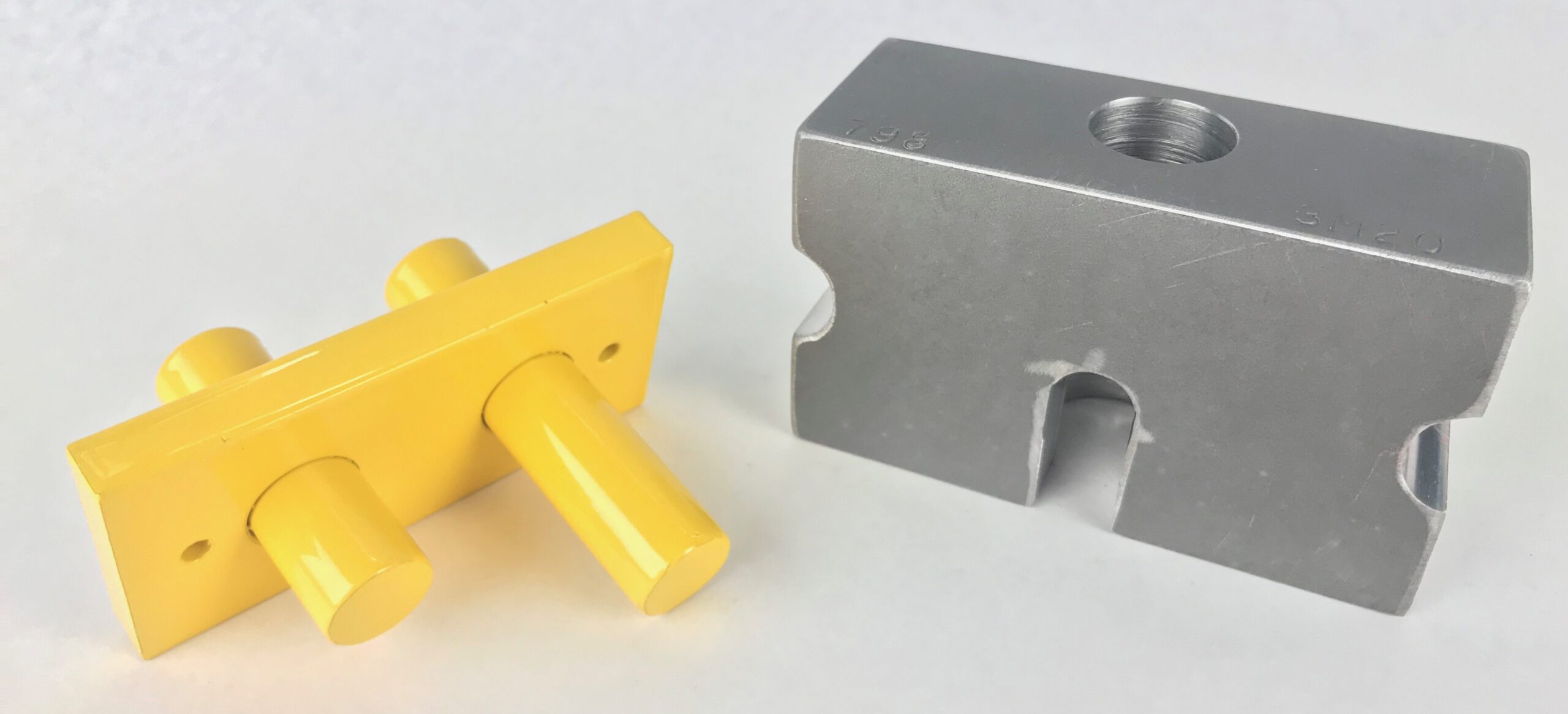 The Huth Tooling adapter for 798 with 801 has two components. The yellow tooling adapted helps fit Huth tooling to BendPak machines. The grey metal die retainer is rectangular-shaped with an arch in the center.