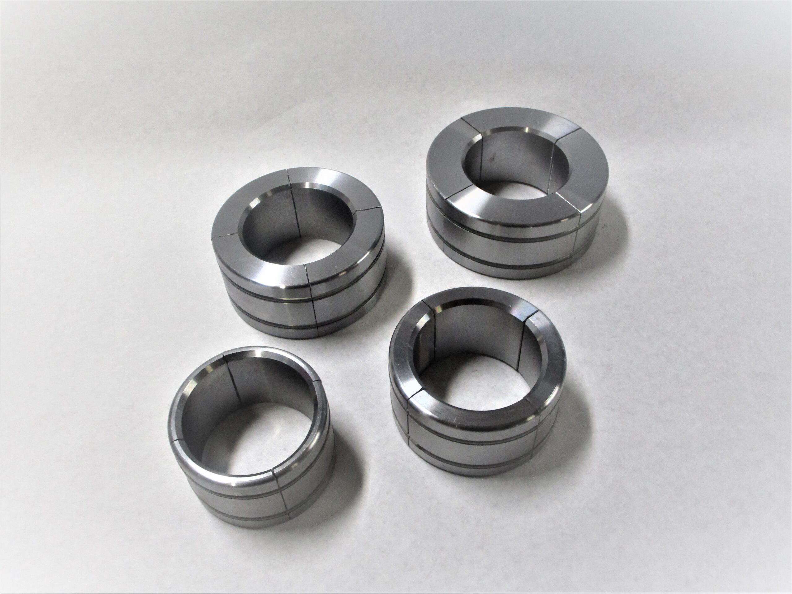 Four silver-colored expander sleeves are pictured against a white background. The sleeves are ring-shaped with varying thicknesses.