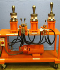 An orange machine shows three tooling heads used for vertical expansion of pipe and tube.