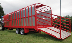 A red livestock trailer is open and parked on green grass. The trailer is made from bent tubing to form the frame of the structure.