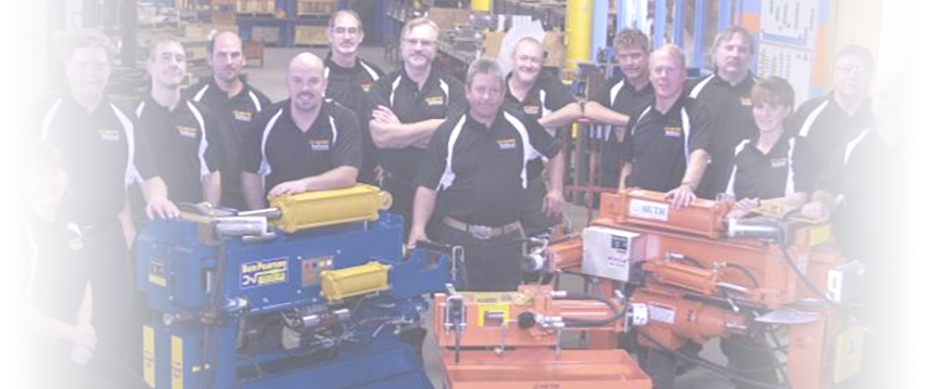 1. A photo of the Huth team in matching polo shirts, standing behind two orange Huth machines and a blue Ben-Pearson machine.