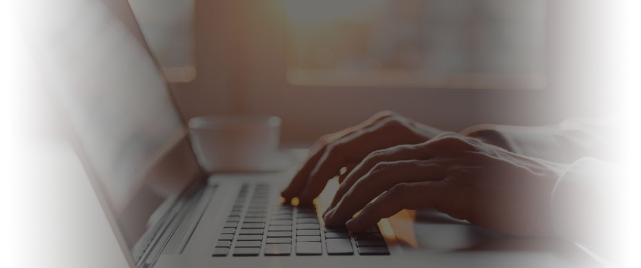 Image shows a closeup cropped photo of a person's hands typing on a laptop keyboard.